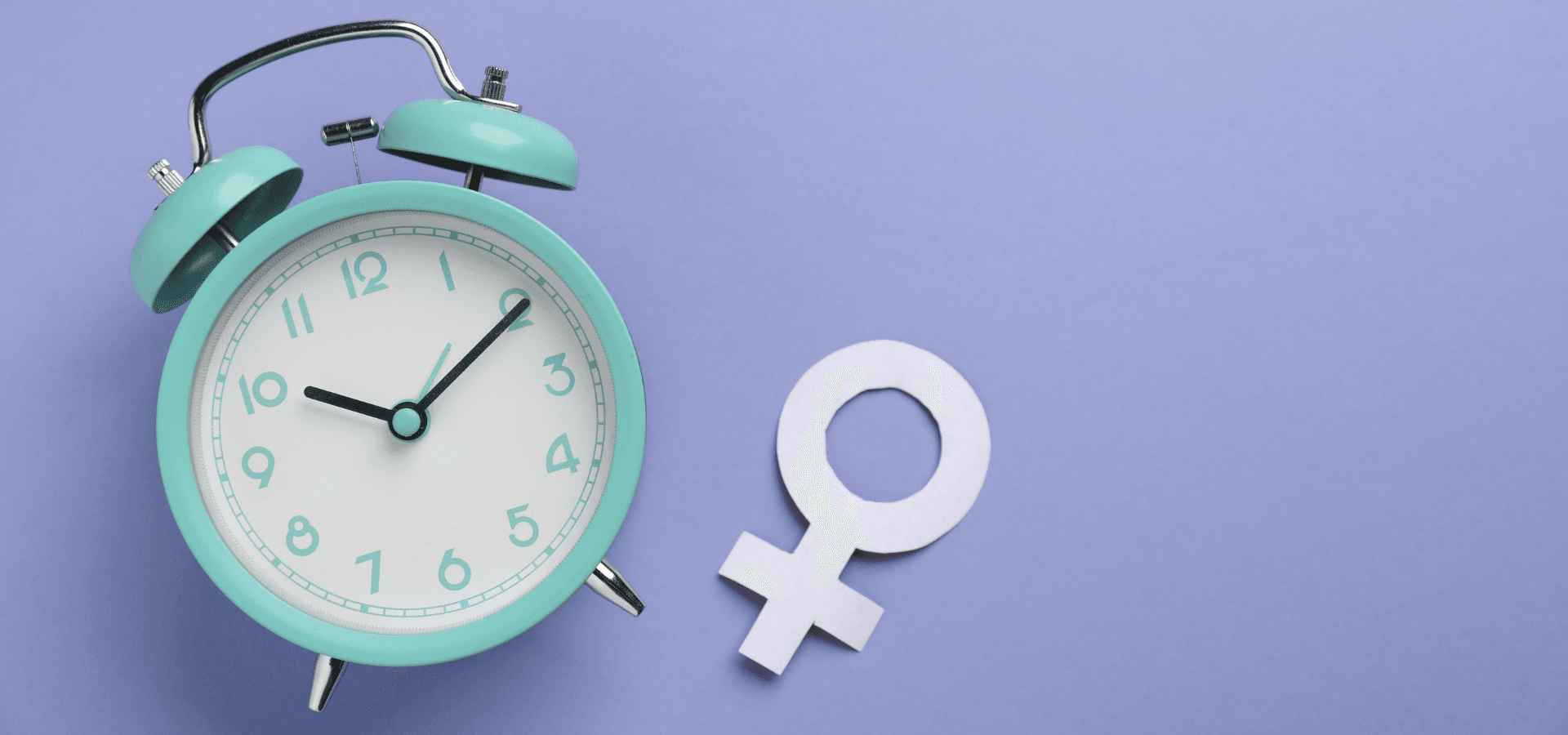 Photo of a turquoise alarm clock with the Venus symbol for the female gender.