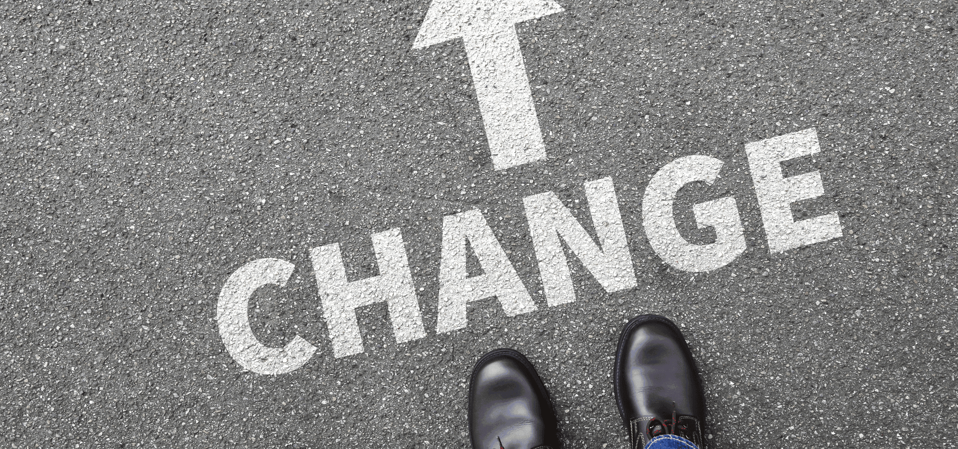 Change logo on concrete floor, arrow pointing to the top and shoes of a person visible under the statement