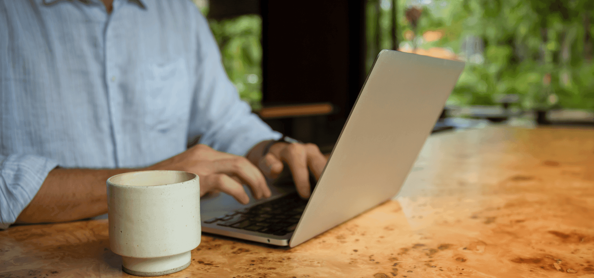 Person working at a laptop on a kitchen counter, on the side a coffee mug, displaying work in politjobs or political jobs.