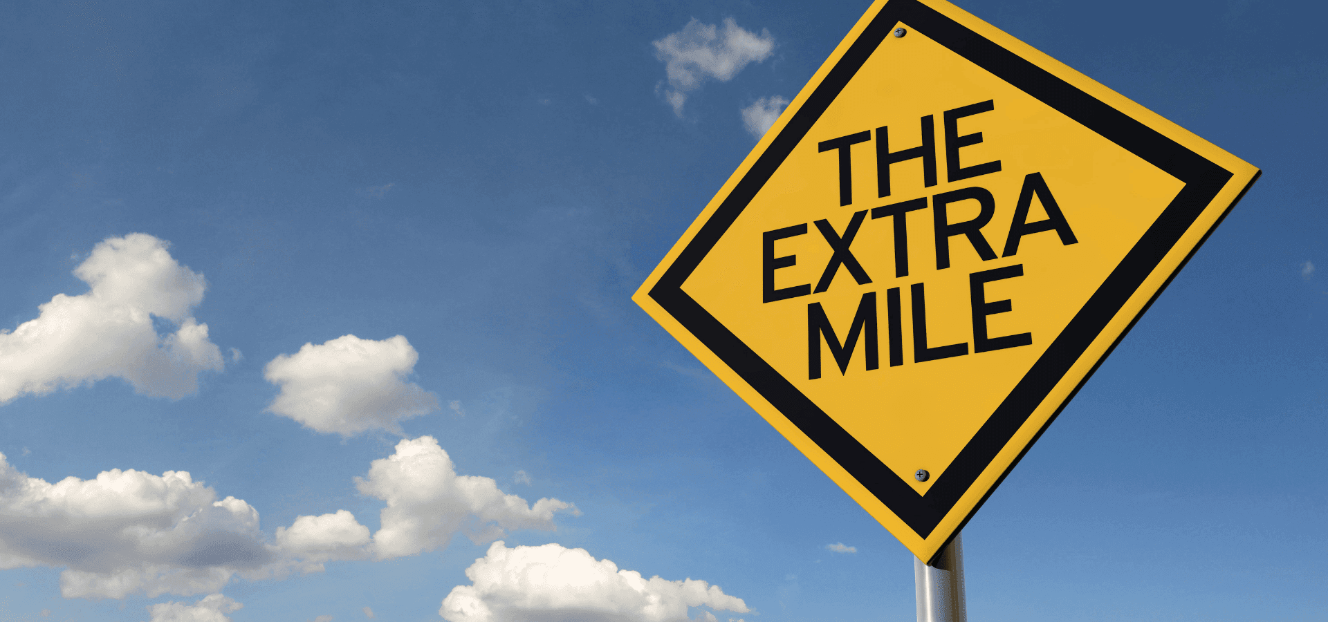 Gelbes Schild mit der Aufschrift „The Extra Mile“.