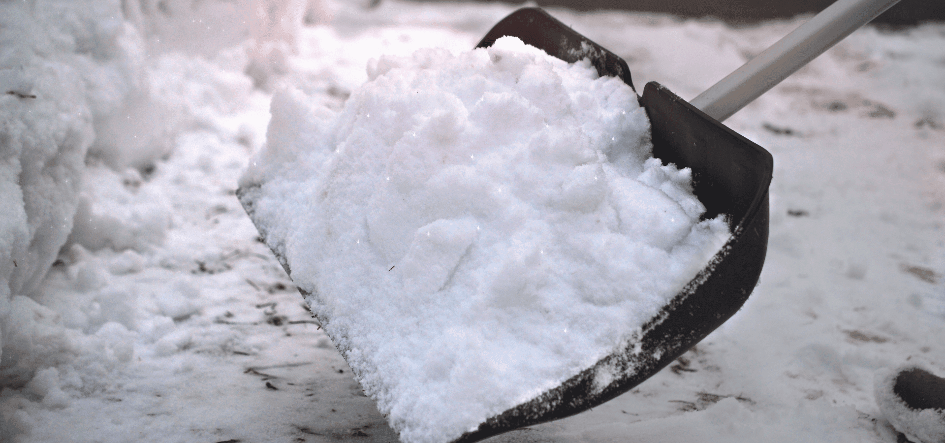 Snow shovel with freshly cleared snow on icy ground – symbolic image of the onset of winter, snow chaos on the way to work, and labor law issues in icy conditions.