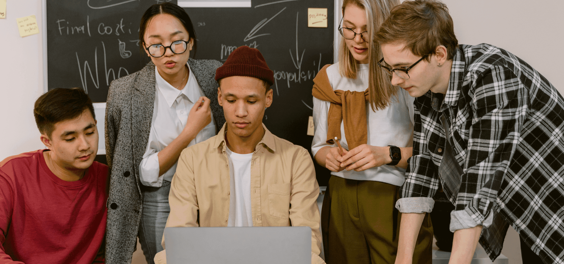 Group of young entrepreneurs sitting behind a laptop working a project together.
