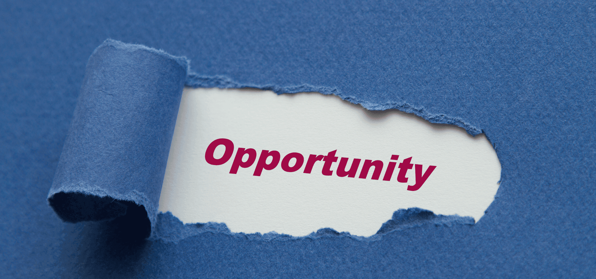 Torn blue paper revealing the word “Opportunity” and symbolically representing new opportunities.